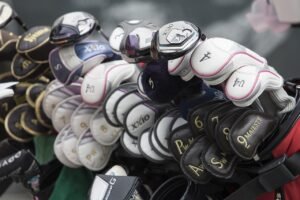 Golf clubs in bags with head covers on, lined up outside.